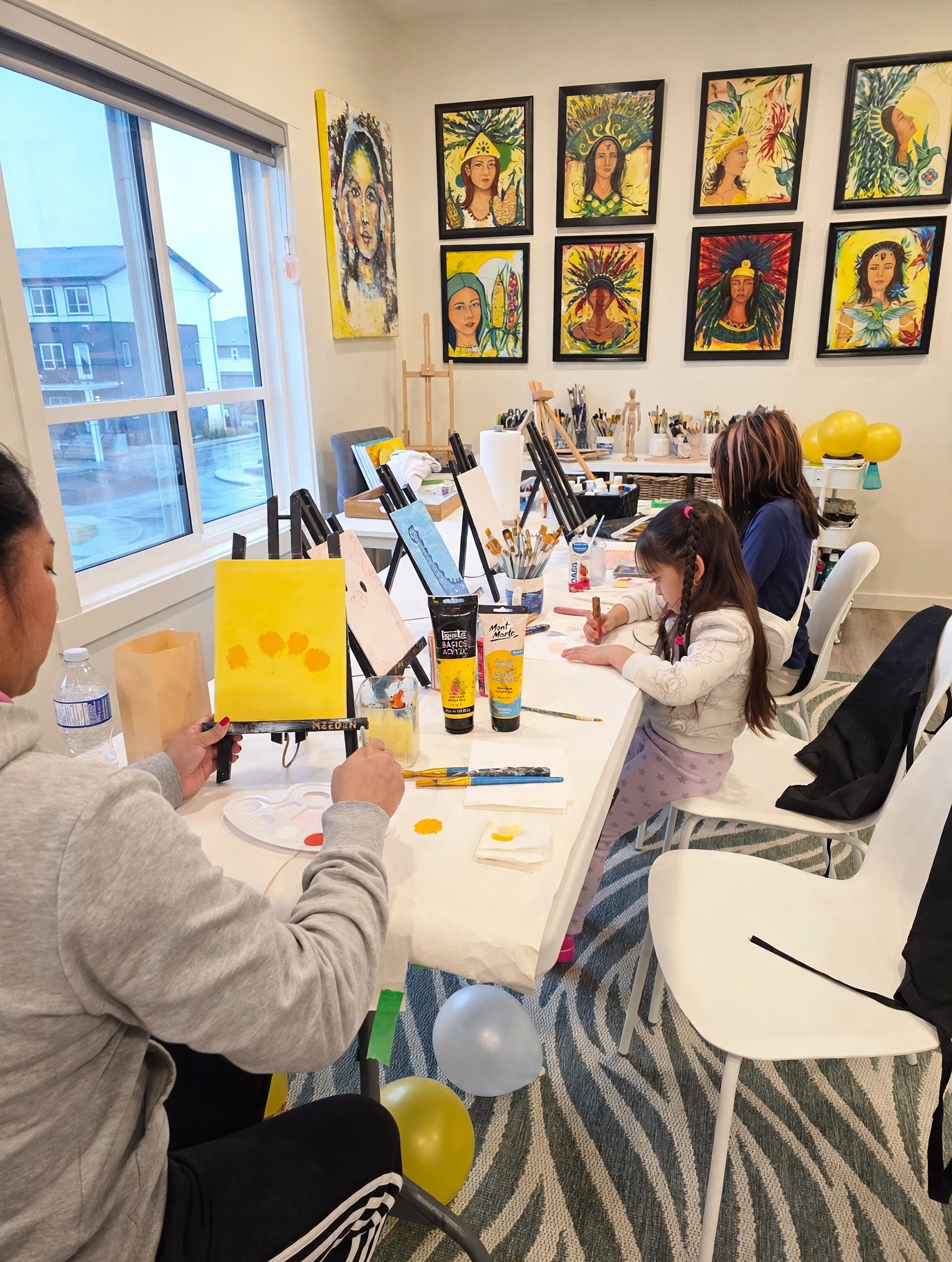 A family painting session with works in progress on easels